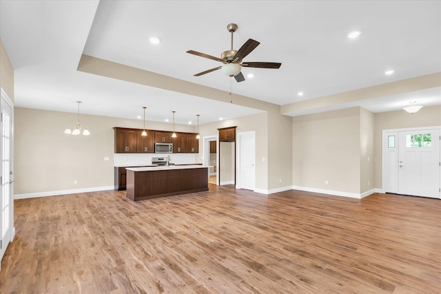 interior space featuring ceiling fan with notable chandelier and light hardwood / wood-style flooring