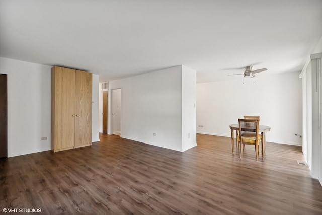 unfurnished living room featuring dark wood-type flooring and ceiling fan