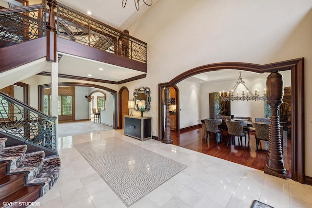 tiled entrance foyer with a towering ceiling, a chandelier, and ornamental molding