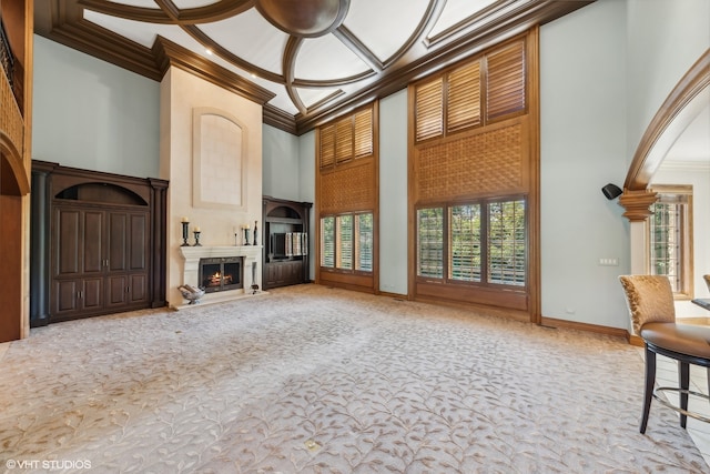 unfurnished living room featuring a high ceiling, coffered ceiling, ornamental molding, and carpet flooring