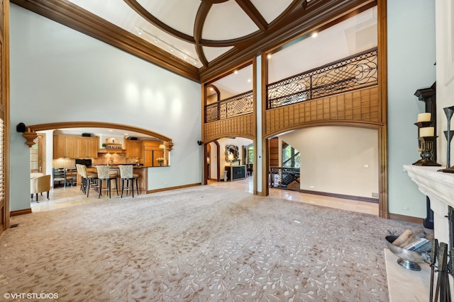 living room with a towering ceiling, ornamental molding, decorative columns, and light tile floors