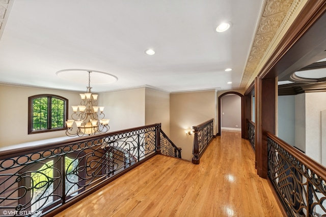 hall with a notable chandelier, crown molding, and light hardwood / wood-style flooring