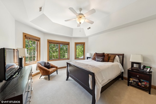 carpeted bedroom with ceiling fan and a tray ceiling