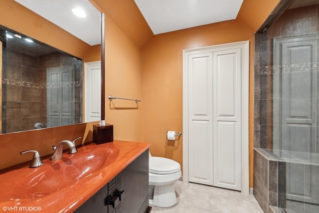 bathroom with tile flooring, tiled shower, toilet, and vanity