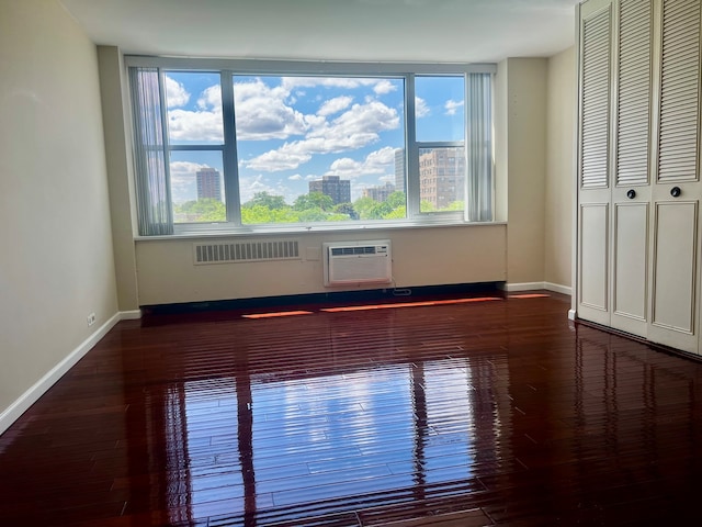 unfurnished room featuring a wall unit AC and dark hardwood / wood-style floors