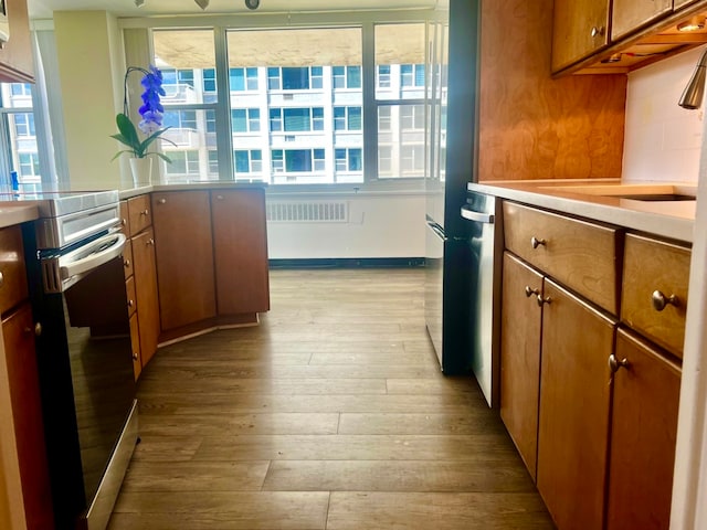 kitchen with light wood-type flooring, backsplash, electric range, and a healthy amount of sunlight