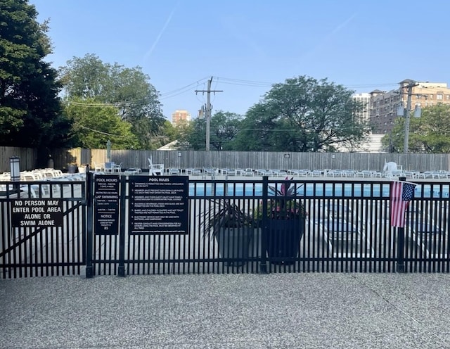 view of gate with a community pool and fence