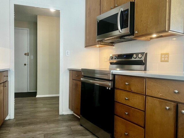 kitchen with backsplash, stainless steel appliances, and dark hardwood / wood-style floors