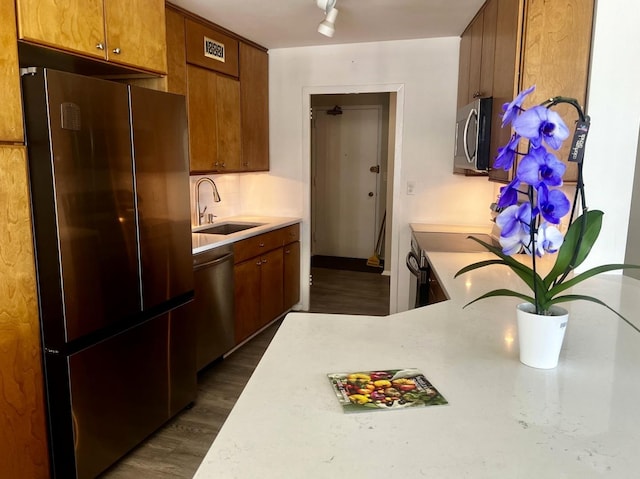 kitchen featuring a sink, appliances with stainless steel finishes, dark wood-style flooring, and light countertops