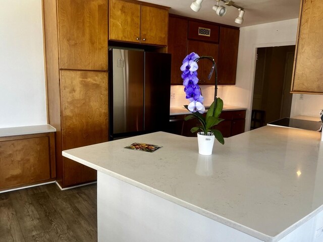 kitchen with black stove, rail lighting, stainless steel fridge, and dark hardwood / wood-style flooring