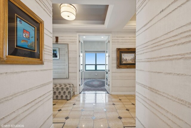 hall with light tile patterned floors and a tray ceiling