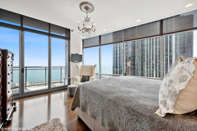 bedroom with an inviting chandelier, access to exterior, floor to ceiling windows, and wood finished floors