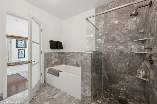 ensuite bathroom featuring marble finish floor, a garden tub, a shower stall, and ensuite bathroom