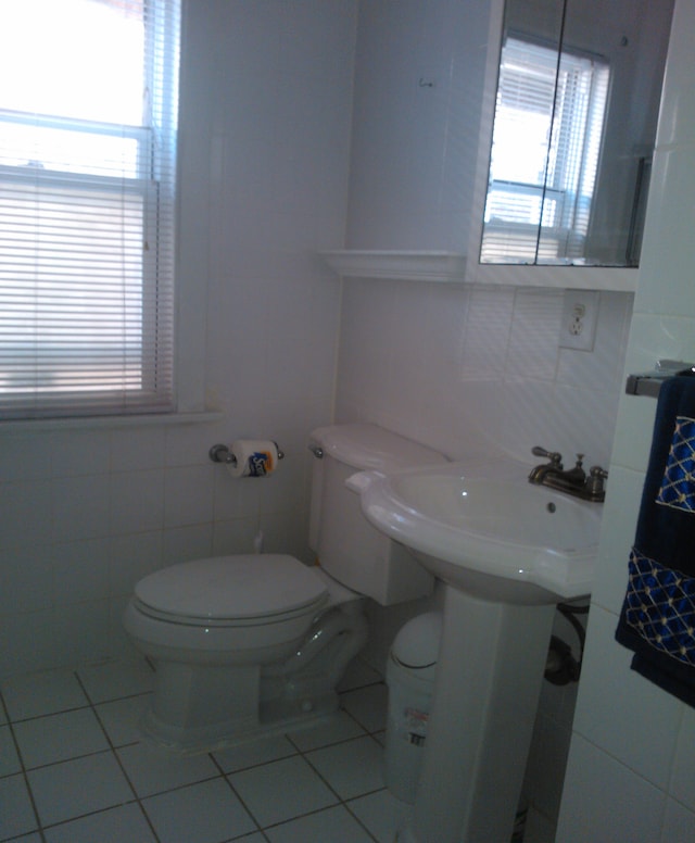 bathroom with tile floors, toilet, and tile walls