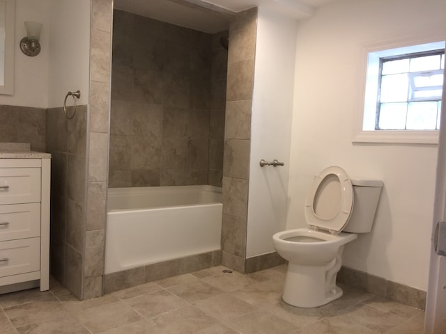 full bathroom featuring tile flooring, tiled shower / bath combo, vanity, and toilet