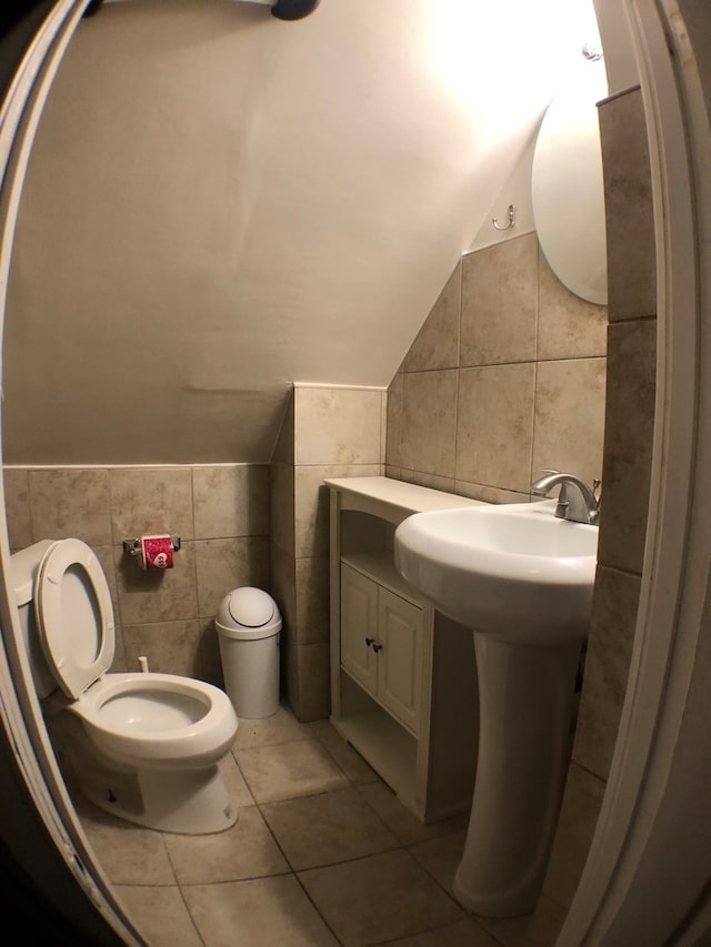 bathroom featuring tile walls, tile flooring, lofted ceiling, and toilet