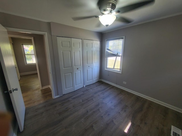 unfurnished bedroom featuring ceiling fan, dark hardwood / wood-style flooring, crown molding, and a closet