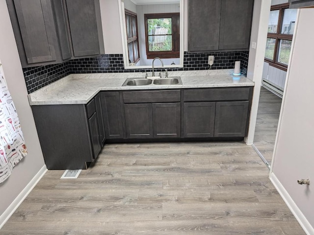 kitchen with decorative backsplash, dark brown cabinets, light wood-type flooring, and sink