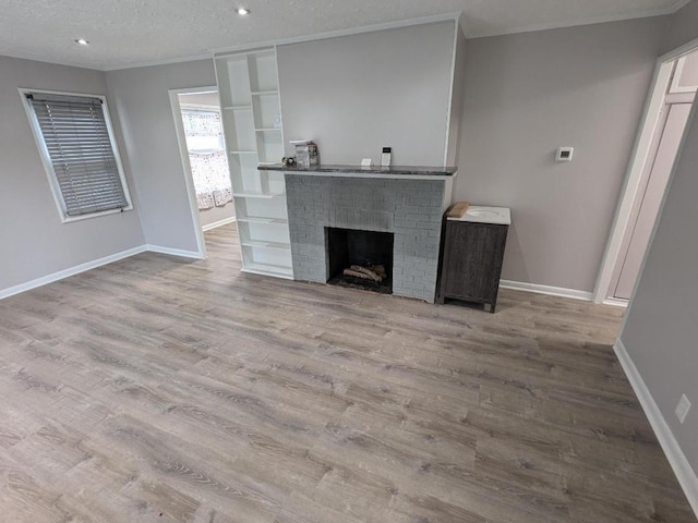 unfurnished living room with a fireplace, a textured ceiling, and light hardwood / wood-style flooring