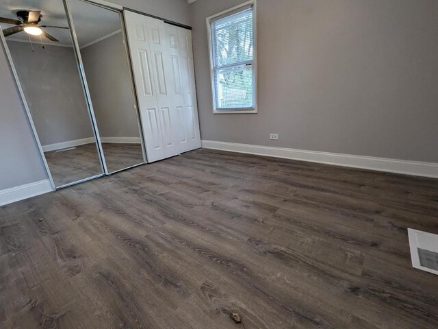 unfurnished bedroom featuring ceiling fan, ornamental molding, and dark wood-type flooring