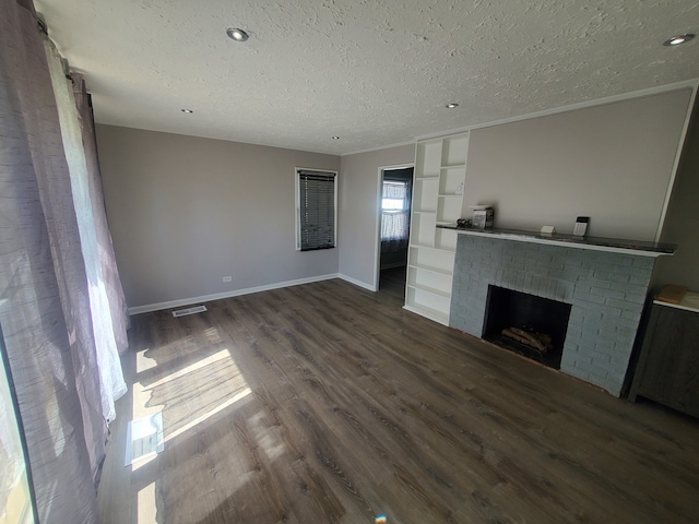 unfurnished living room with hardwood / wood-style floors, a textured ceiling, and a brick fireplace