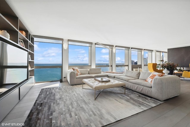 living room with hardwood / wood-style floors, a water view, and a wall of windows