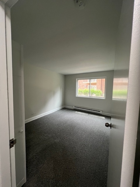 spare room featuring carpet floors and a baseboard radiator