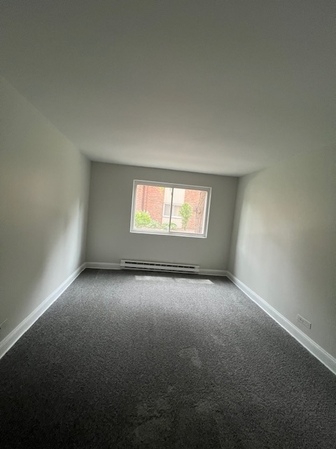 carpeted spare room with baseboard heating