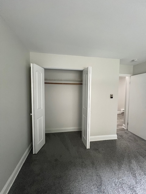 unfurnished bedroom featuring dark colored carpet and a closet