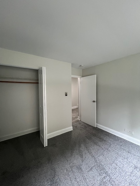 unfurnished bedroom with a closet and dark carpet