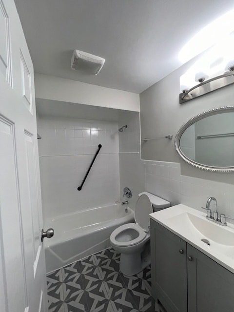 full bathroom featuring tile flooring, tile walls, tiled shower / bath combo, vanity, and toilet