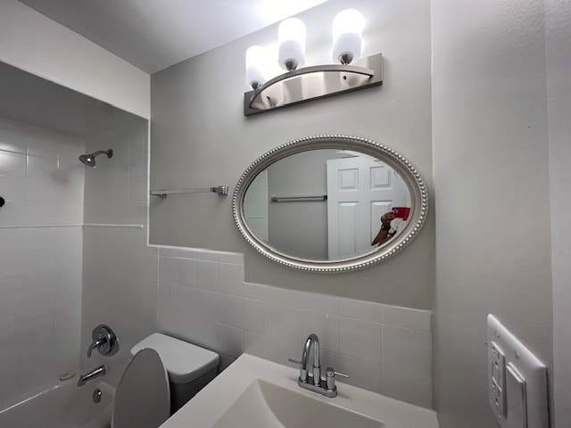 full bathroom featuring tiled shower / bath, sink, and toilet