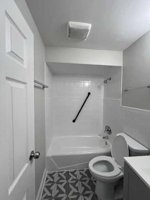 full bathroom featuring tile floors, tiled shower / bath combo, vanity, and toilet