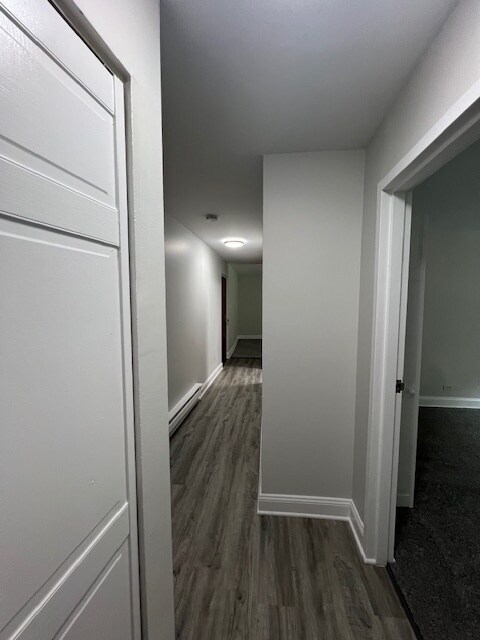 hall with dark hardwood / wood-style flooring and baseboard heating