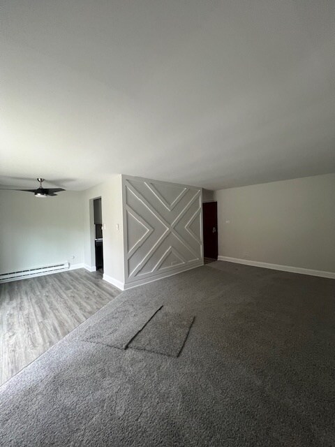 spare room with a baseboard heating unit, carpet flooring, and ceiling fan