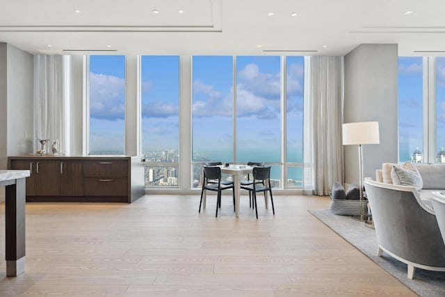 dining area with a water view, a wall of windows, and light hardwood / wood-style flooring