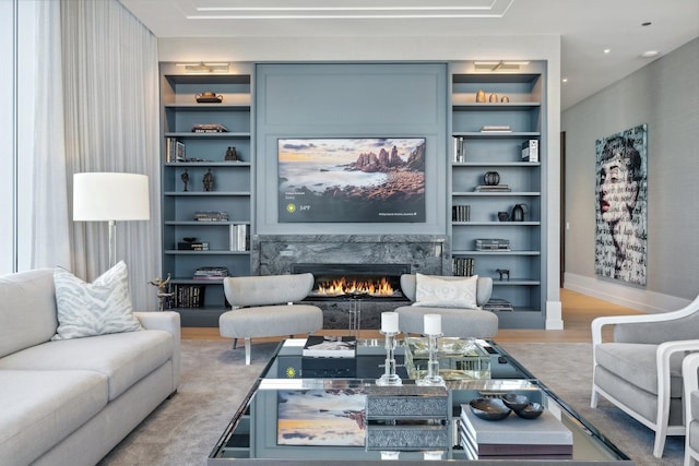 living room featuring wood-type flooring, built in features, and a premium fireplace