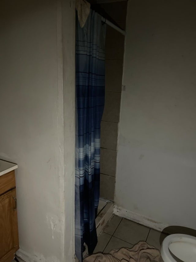 bathroom with tile floors, a shower with shower curtain, toilet, and vanity