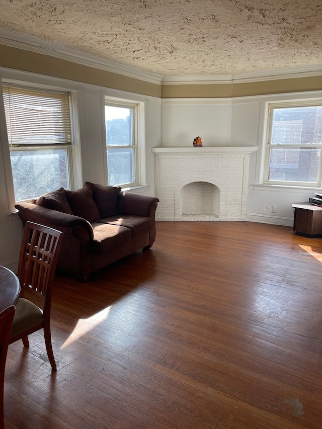 living room featuring a wealth of natural light, dark wood-type flooring, a brick fireplace, and a textured ceiling