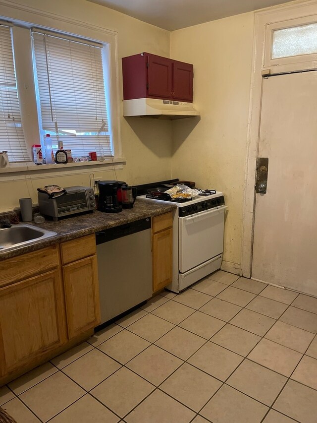 kitchen featuring white gas range oven, custom range hood, stainless steel dishwasher, and light tile flooring