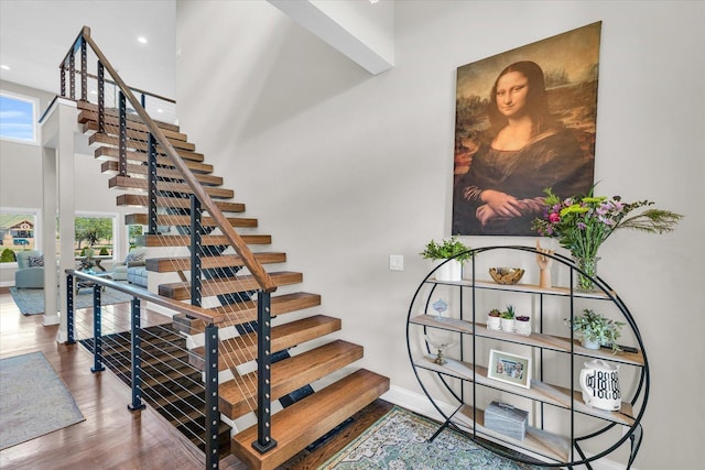 staircase featuring hardwood / wood-style flooring and a high ceiling