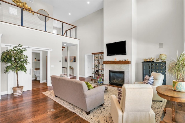 living room featuring a towering ceiling, dark hardwood / wood-style floors, and a tile fireplace