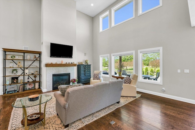 living room with a high ceiling, a tiled fireplace, and dark hardwood / wood-style floors