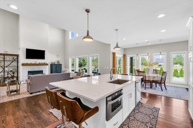 kitchen with hanging light fixtures, sink, a center island with sink, and white cabinets