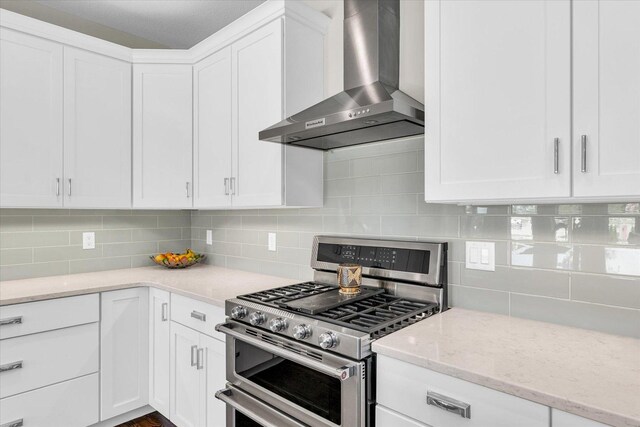 kitchen featuring white cabinetry, double oven range, decorative backsplash, and wall chimney exhaust hood