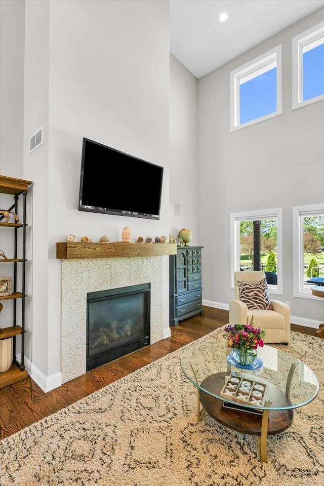 living room featuring a high ceiling, a tile fireplace, and dark hardwood / wood-style floors