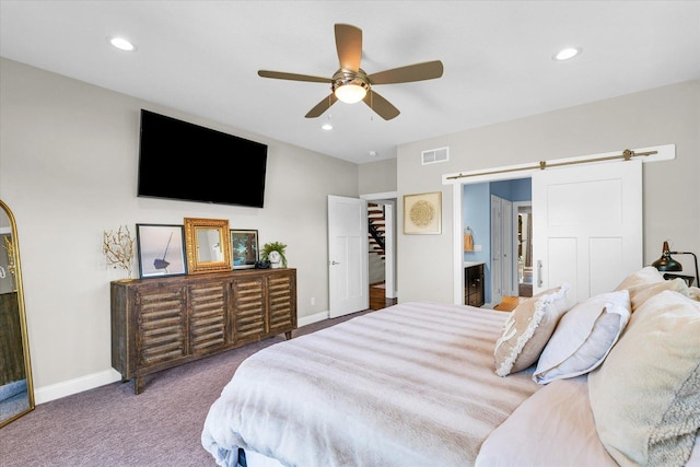 carpeted bedroom featuring ceiling fan, a barn door, and ensuite bath