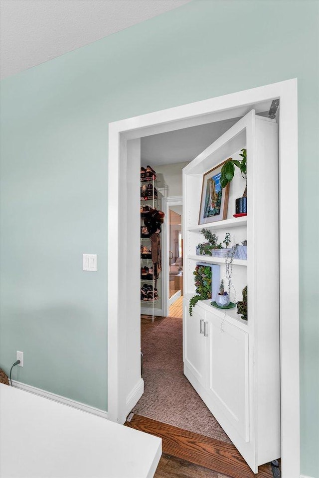 hall with dark colored carpet