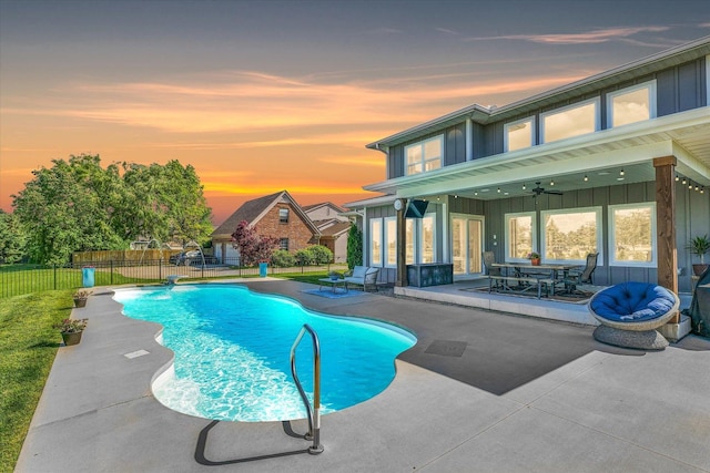 pool at dusk featuring pool water feature, a patio, and ceiling fan