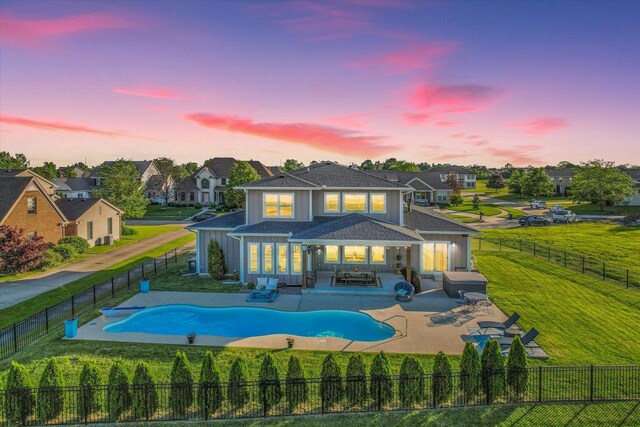 back house at dusk featuring a yard, a fenced in pool, an outdoor living space, and a patio area